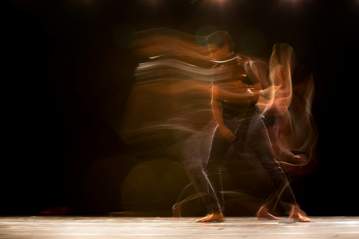 Motion-blurred figure moving through warm stage light